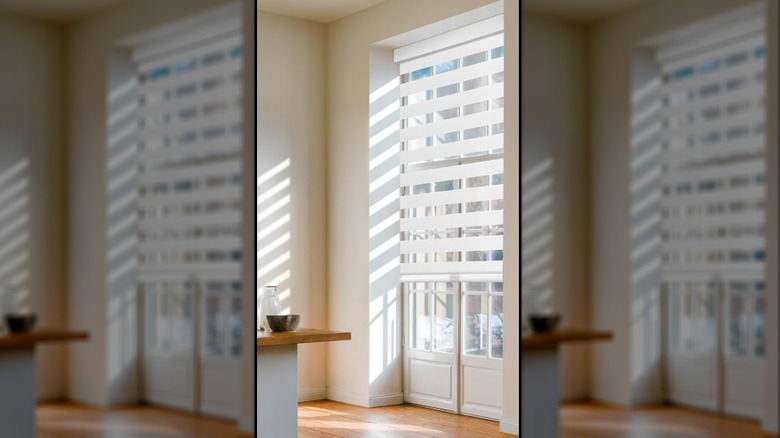 French doors looking out onto a small balcony are covered with white zebra blinds.