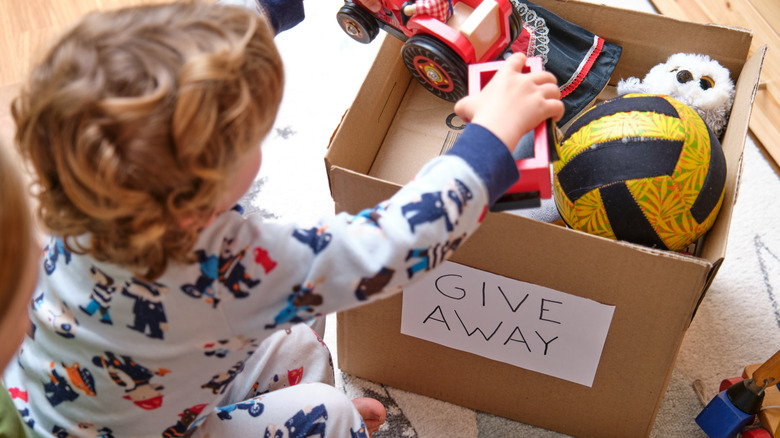 Small child putting toys in a box to give away