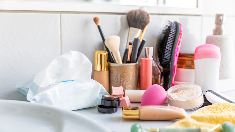 Bathroom vanity cluttered with makeup and toiletries