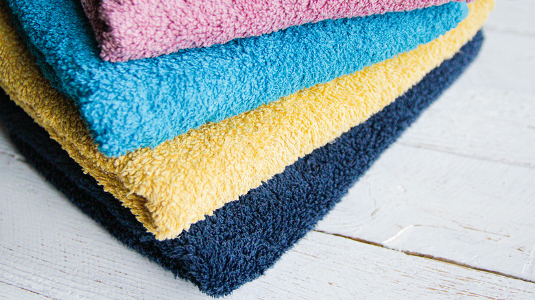 Pink, light blue, yellow, and dark blue towels folded in a pile