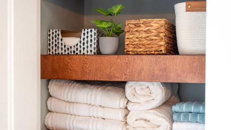 Open shelves in a bathroom with towels, baskets, and tissues