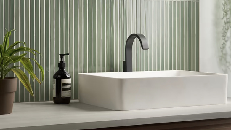 Pedestal sink with green fluted tile backsplash.