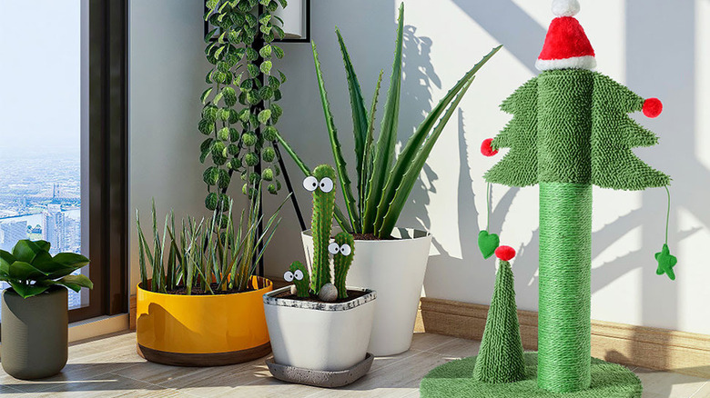 A Christmas tree cat scratching post with Santa hat sits next to various potted plants