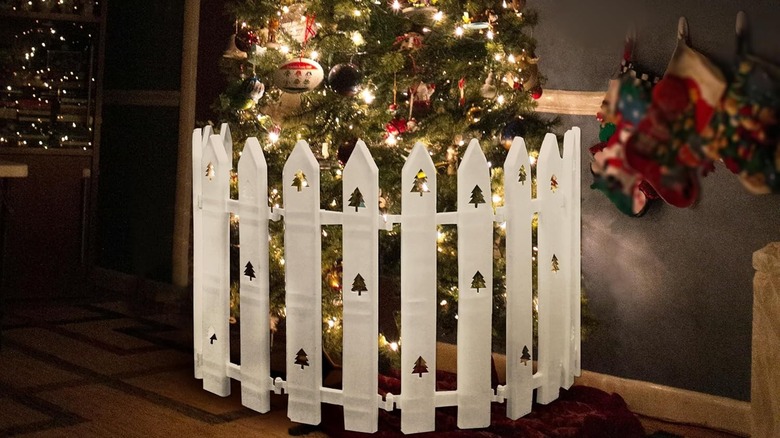 A white plastic fence is erected around a decorated lit Christmas tree