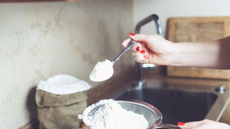 person adding flour to sink