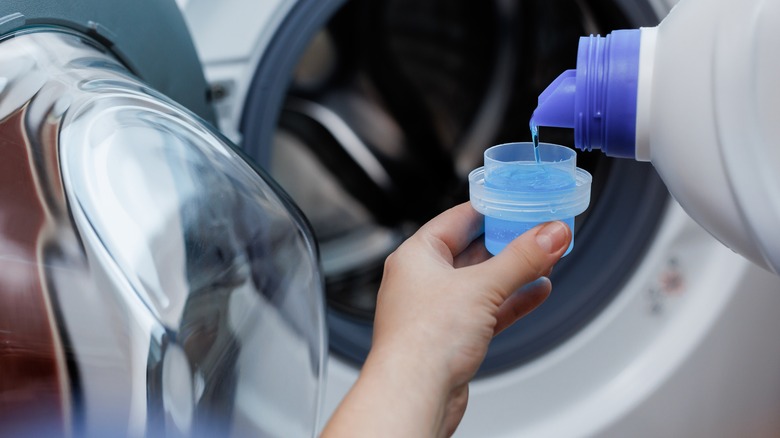 Hand pouring laundry detergent