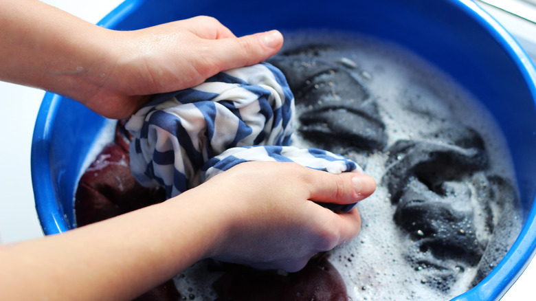 hand washing clothes in basin