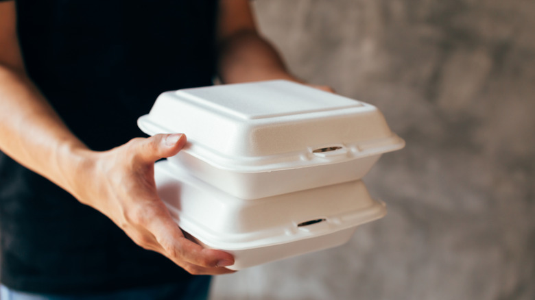 Person carrying styrofoam takeout boxes