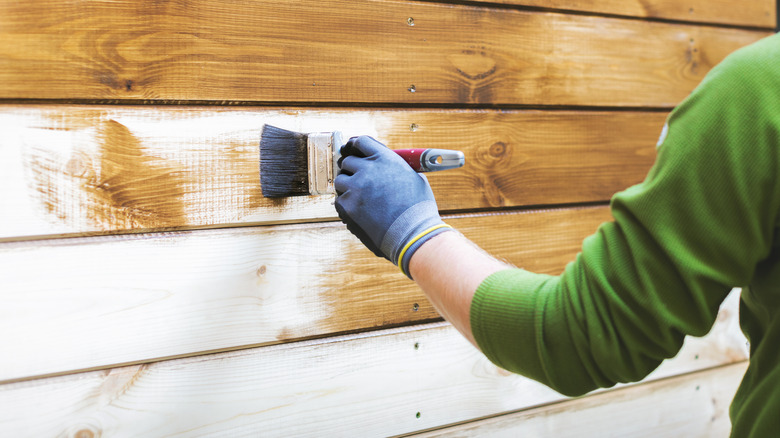 person painting wood house siding