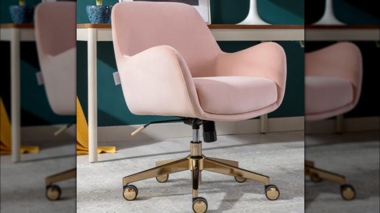 A pink velvet office chair with gold base sits in a home office