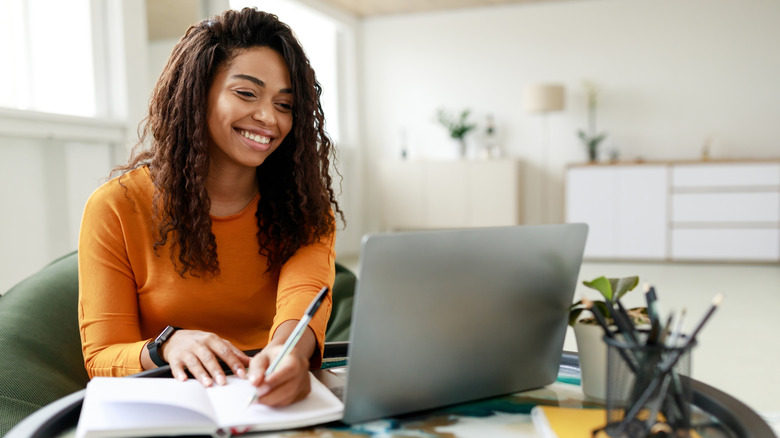 Woman working from home with laptop and journal