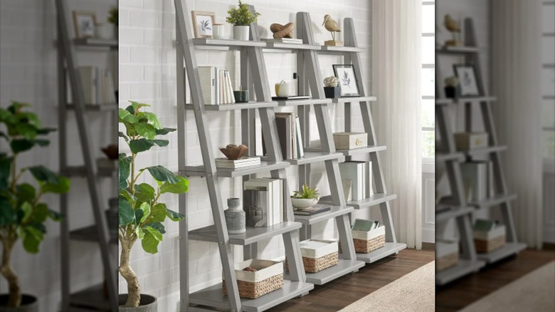 A light gray ladder bookcase holds supplies in a laundry room