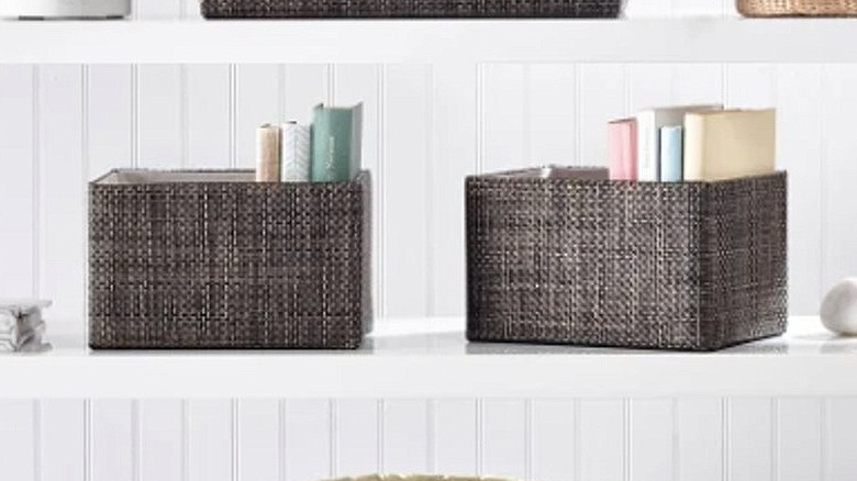 Four woven storage baskets sit across three white shelves.