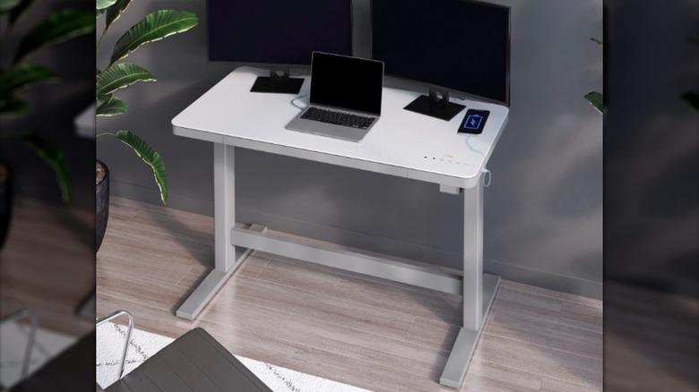 A small white metal desk with laptop and two monitors on it