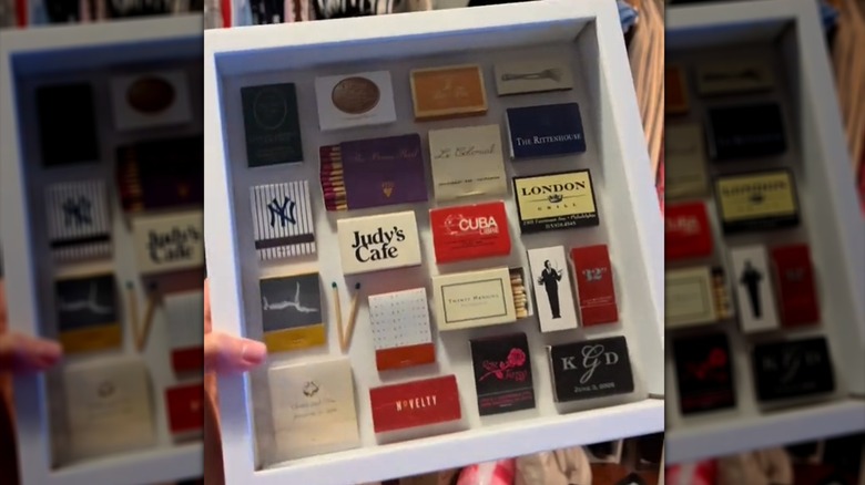 Hand holds white shadow box filled with matchbooks