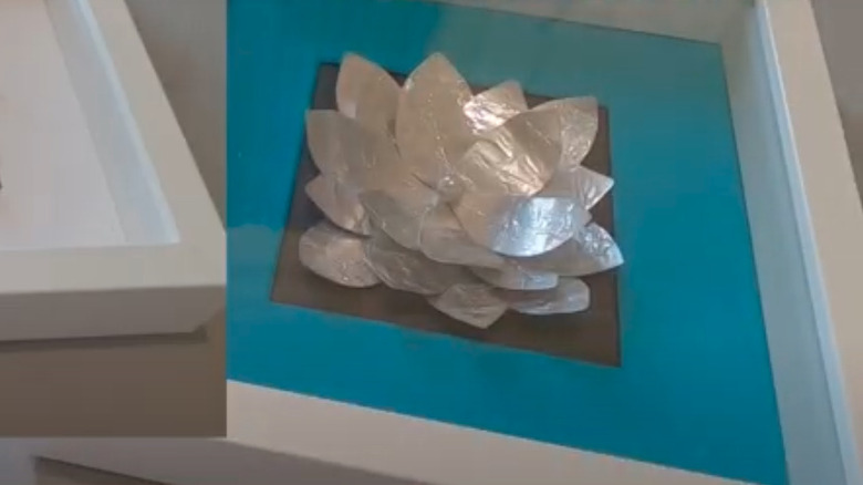 Metal flower made of tea light cups in shadow box