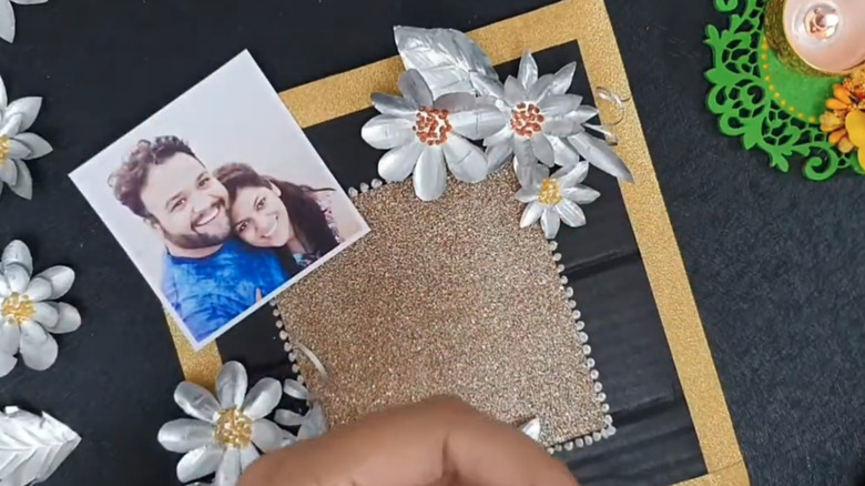 Picture next to a picture frame made of cardboard and metal flowers