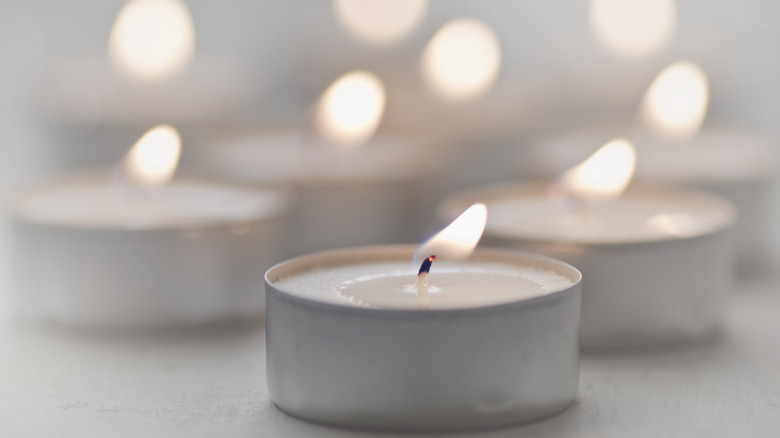 Lit tea light with selective focus in front, background of blurred tealights