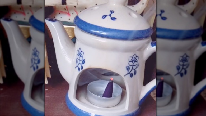 Cone of incense inside of a tea light holder inside a teapot shaped incense burner