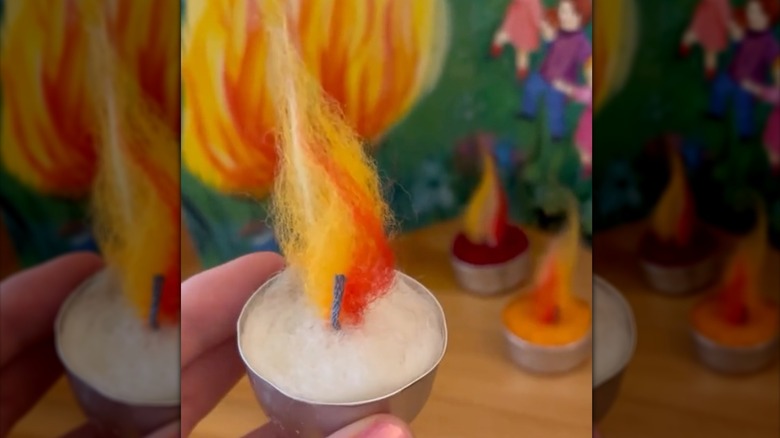 Hand holding a needle felted candle made inside of a tea light cup