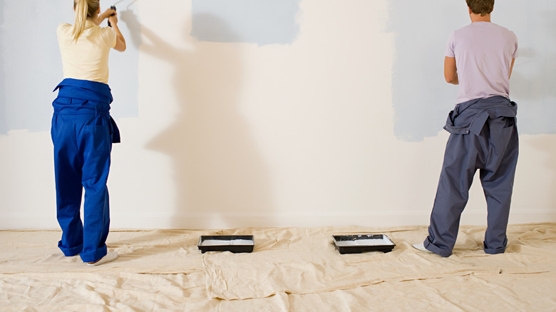 Man and woman painting wall