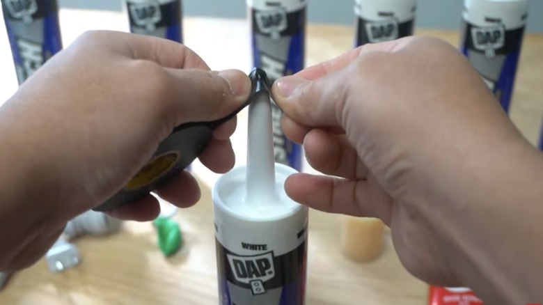 person sealing caulk tube with tape