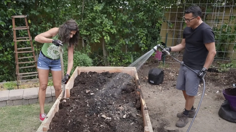 couple filling raised garden bed