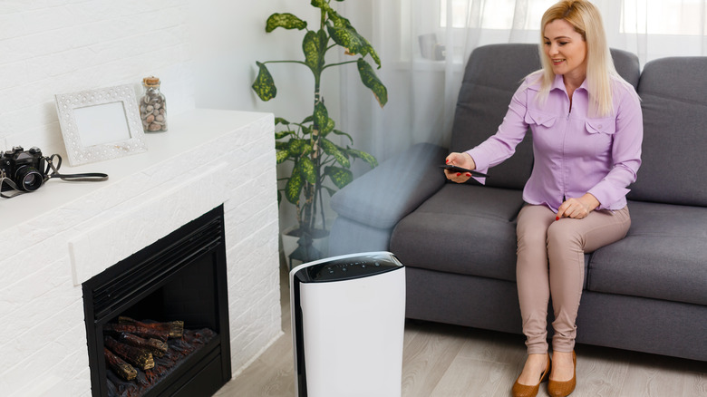 Woman using remote control for humidifier