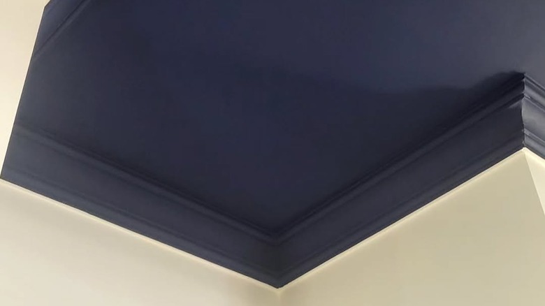 A deep blue ceiling with matching crown molding over a white wall.