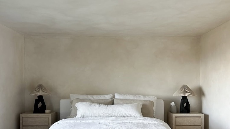 A room with bed and limewash walls and ceiling.