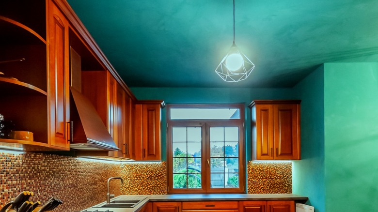 A kitchen with teal ceiling and natural wood cabinetry.