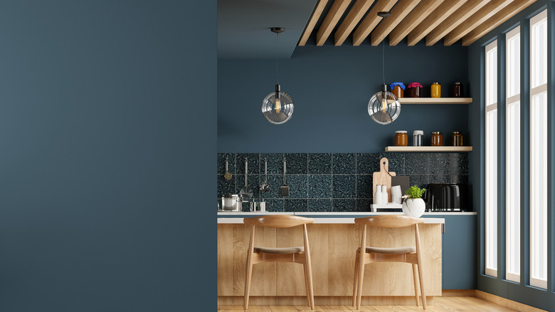 A modern kitchen with dark teal walls and ceiling and wooden exposed beam accents.