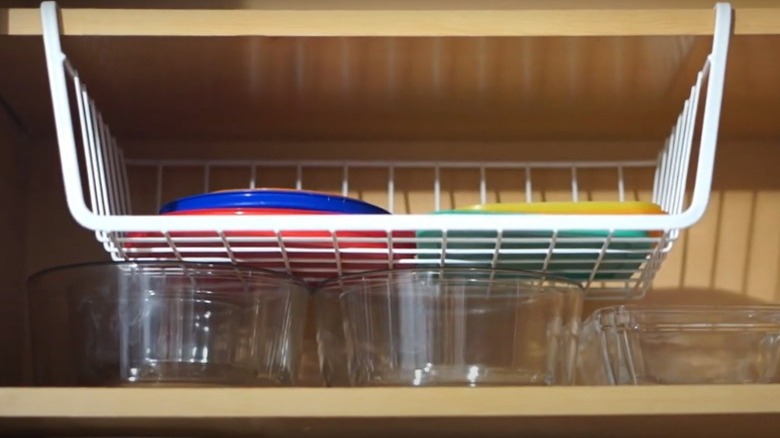 A hanging shelf organizer holding plastic lids