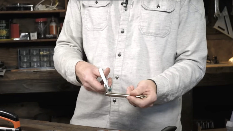 man sharpening scissors on drill bit