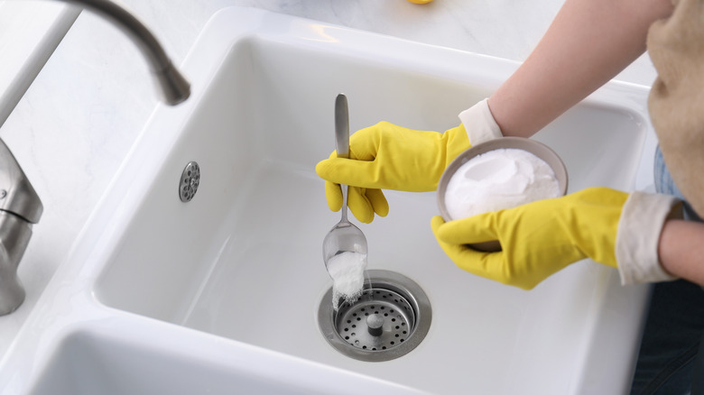 hands scooping baking soda sink