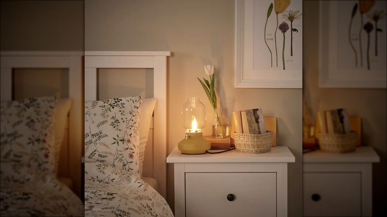 A warm light sits on a bedside table