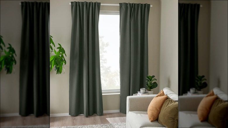 Dark green blackout curtains hang in a living room