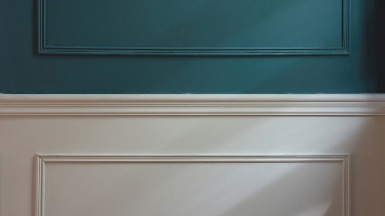 White rown molding above paneling on blue wall