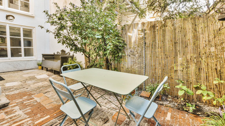 Bamboo fence shown in a backyard near trees