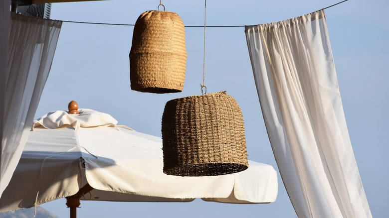 White curtains hanging outside near decorative basket chandeliers