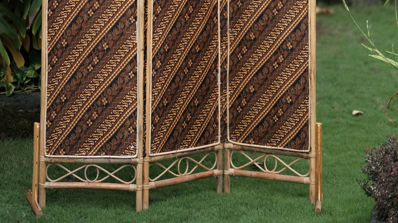 A tan and brown room divider outside near trees