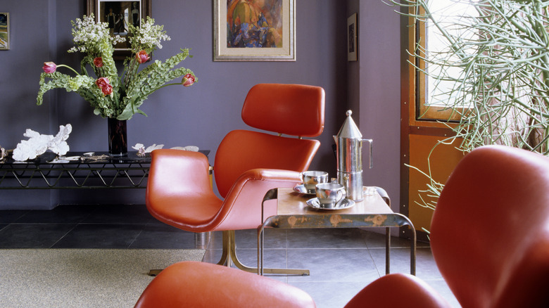 Mauve walls in living room with orange furniture.