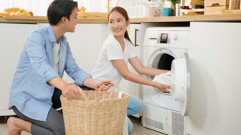 Couple doing laundry at home using washing machine