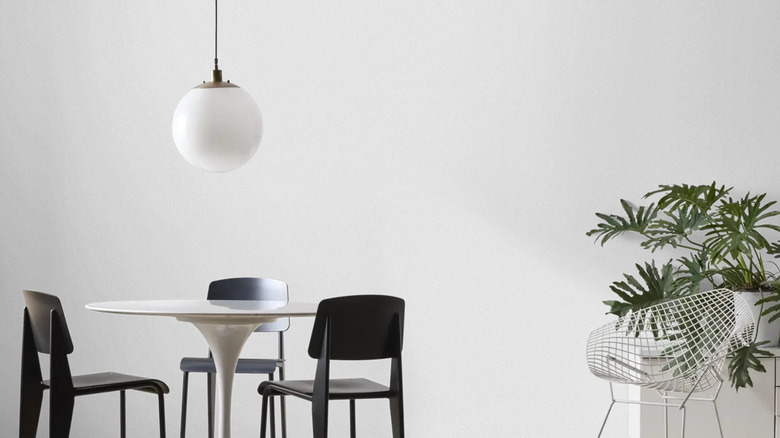 An image of a small kitchen table, a light fixture, and a plant before a wall painted Knitted Needle