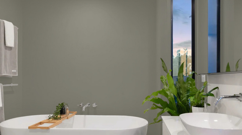 A bathroom with Mountain Road on the walls behind a white tub and potted plants