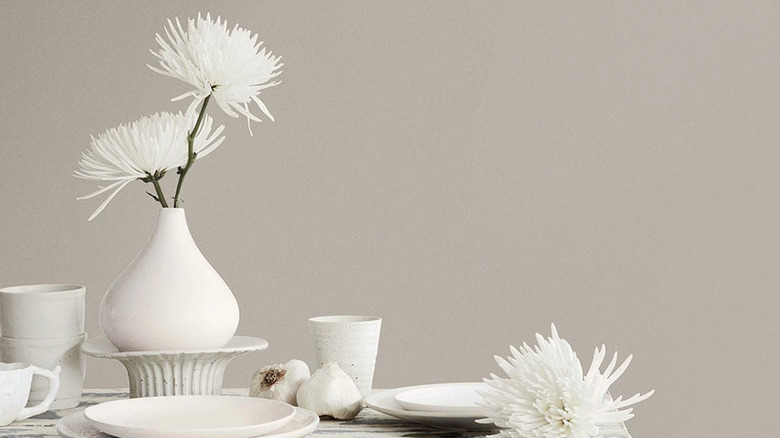 An image with white dishes, flowers, and garlic in front of a wall painted with Requisite Gray