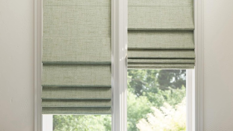 sage green roman blinds side-by-side at different heights