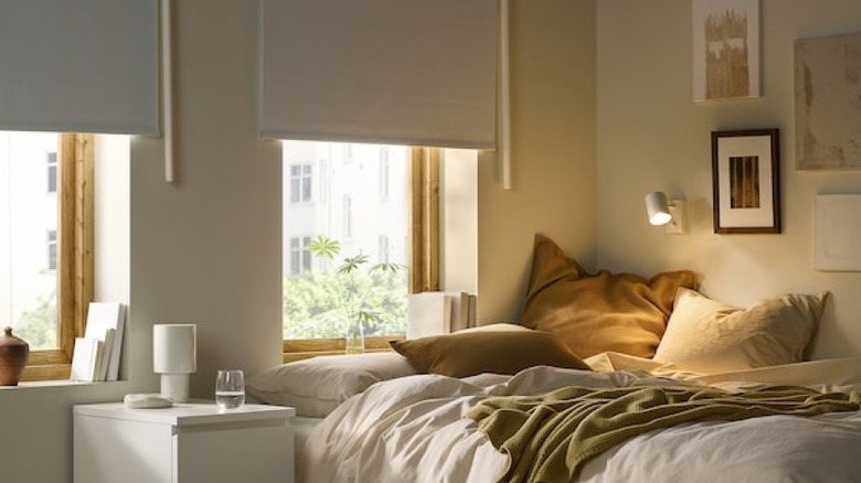 half-closed blackout shades next to messy neutral colored bedroom