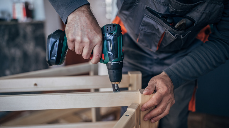 A person using a cordless drill to build furniture