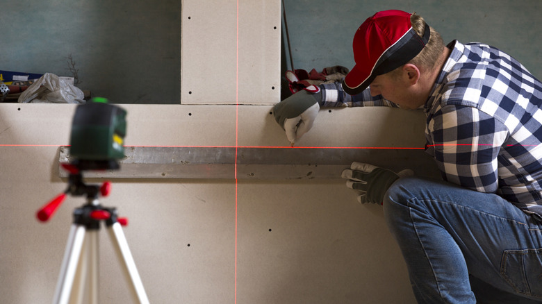 Man using a laser level on wall